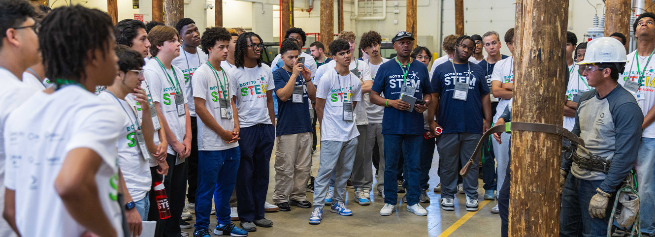 Boys of STEM gathering around a utility pole climbing demonstration
